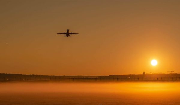 Airplane taking off at sunrise symbolizing departure transformation and possibility